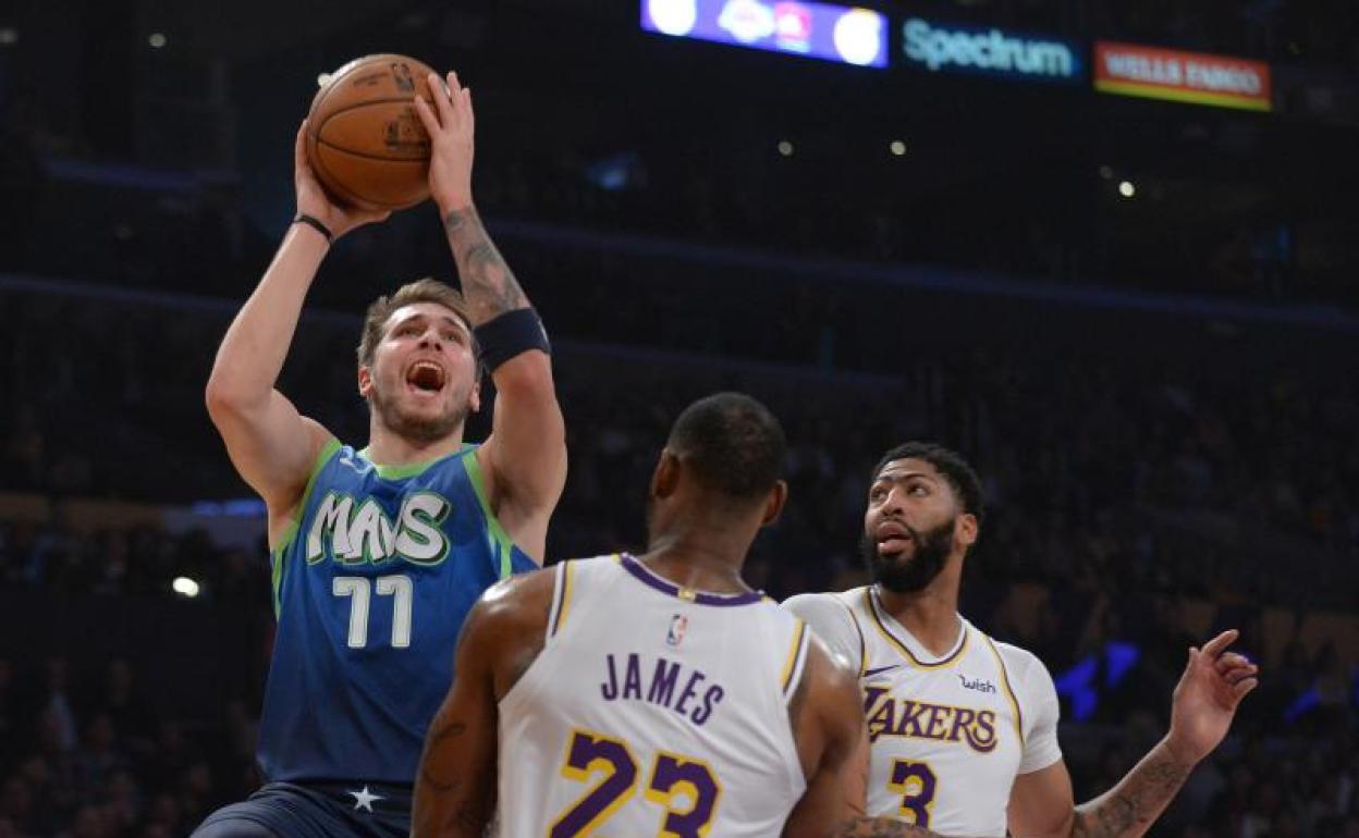 Luka Doncic lanza a canasta pese a la oposición de LeBron James. 