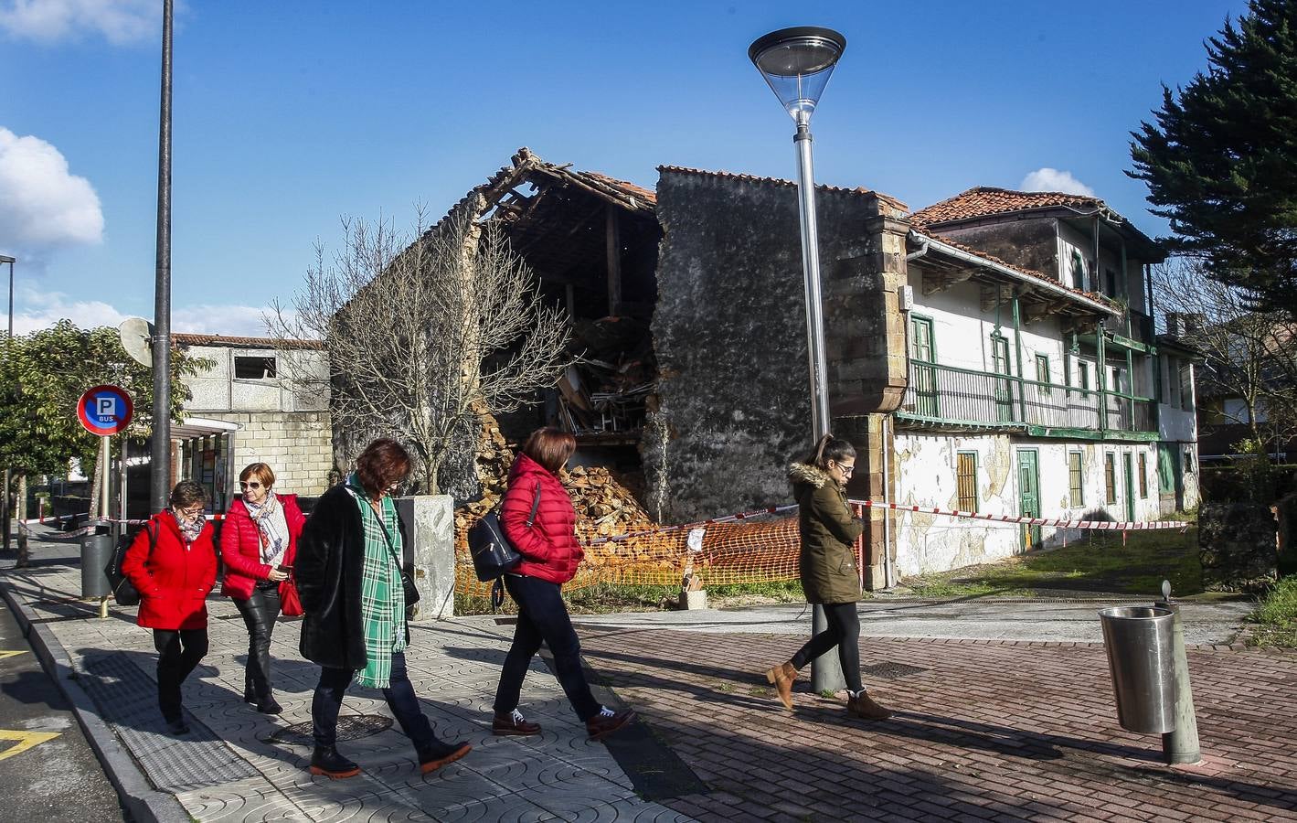 Varias mujeres pasan cerca del inmueble, acordonado por los bomberos tras el derrumbe de una fachada.