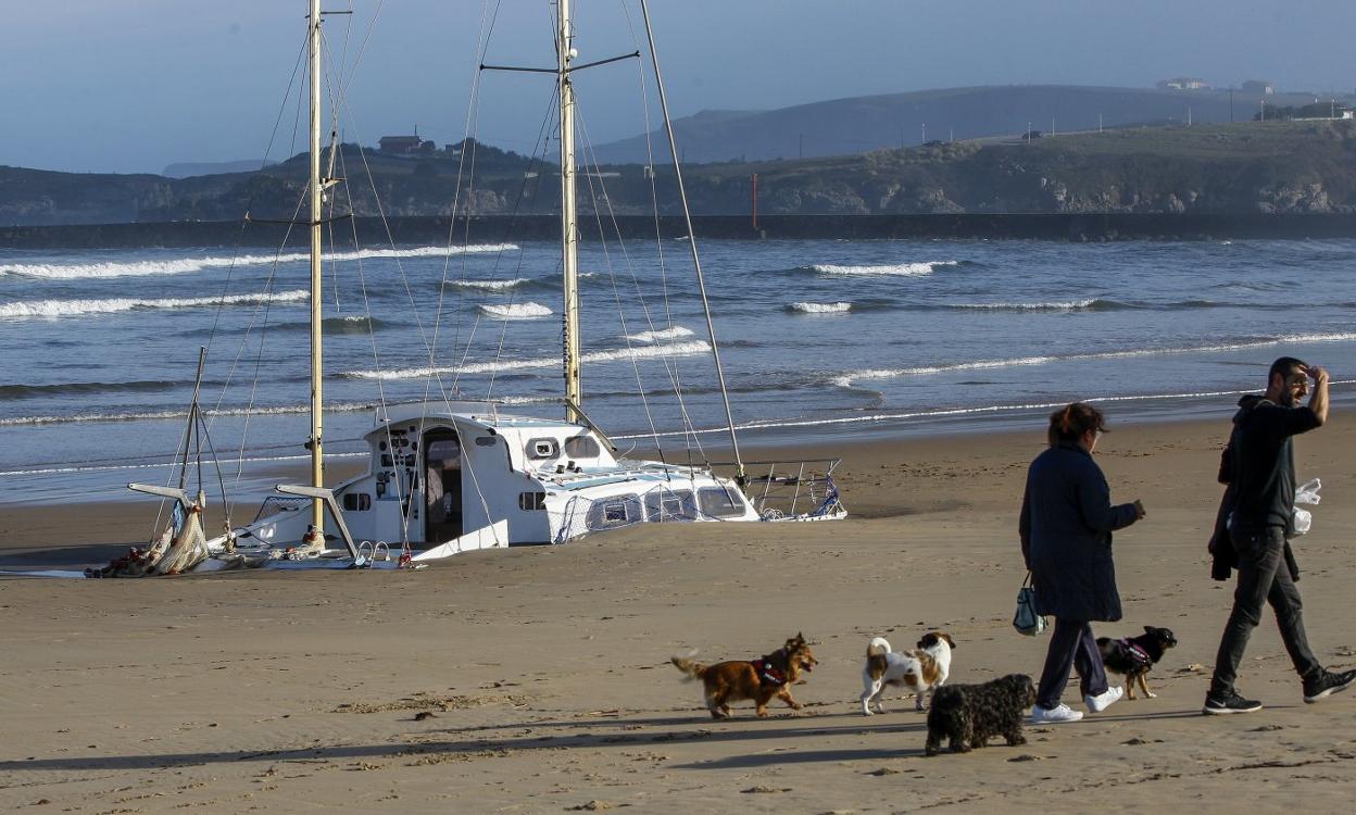 El catamarán, tras naufragar y ser arrastrado por el viento, llegó a la playa de La Concha, en Suances, donde permanece hundido y cubierto de arena. 