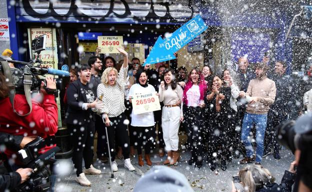 Un grupo de personas celebran en la administración madrileña de Doña Manolita que ha vendido el número 26.590, agraciado con el Gordo de Navidad