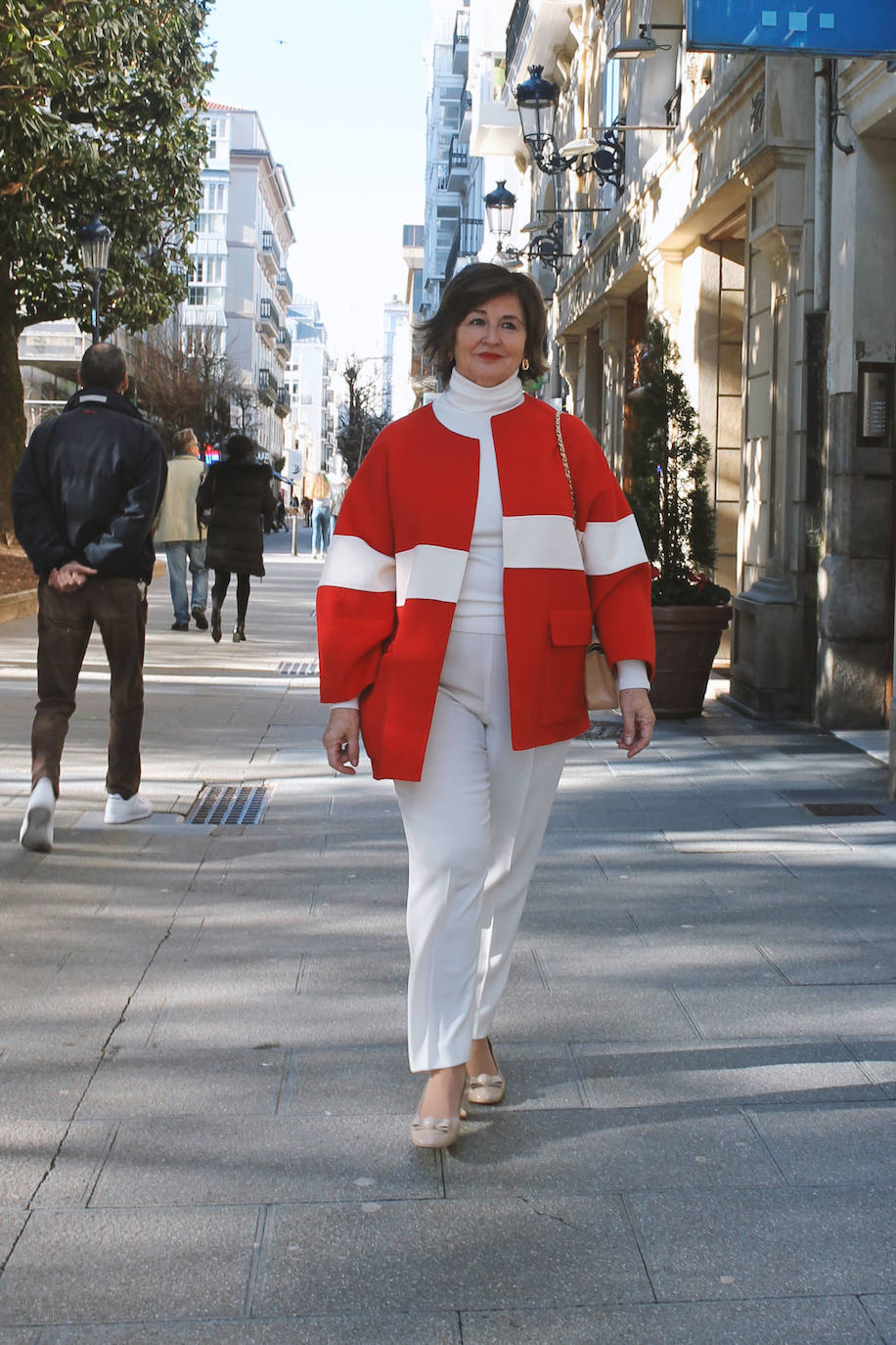 'Total look' de pantalón y jersey de cuello ato blanco con abrigo sin cuello acampanado rojo y blanco, accesorios dorados.