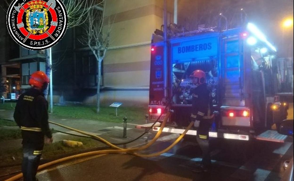 Dos bomberos trabajan para extinguir el incendio del garaje.