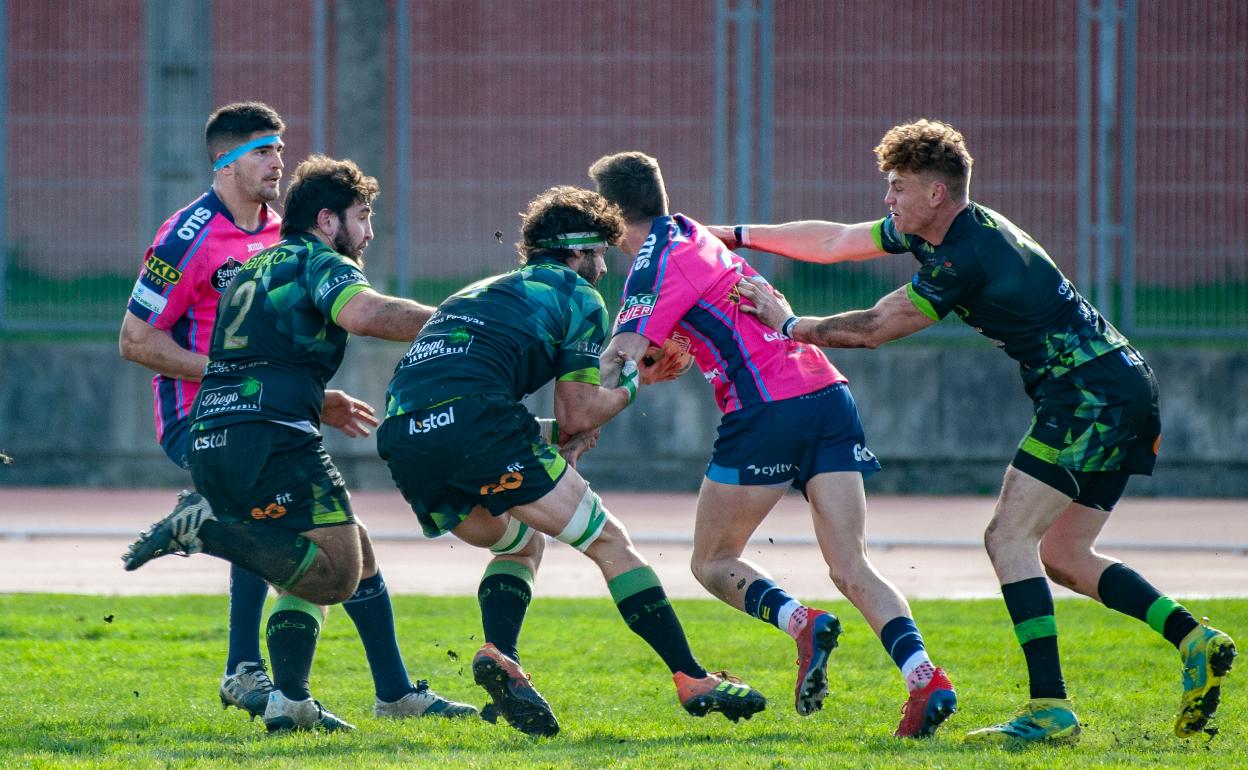Tres jugadores del Bathco intentan placar a un rival del Quesos en el partido en el Ruth Beitia