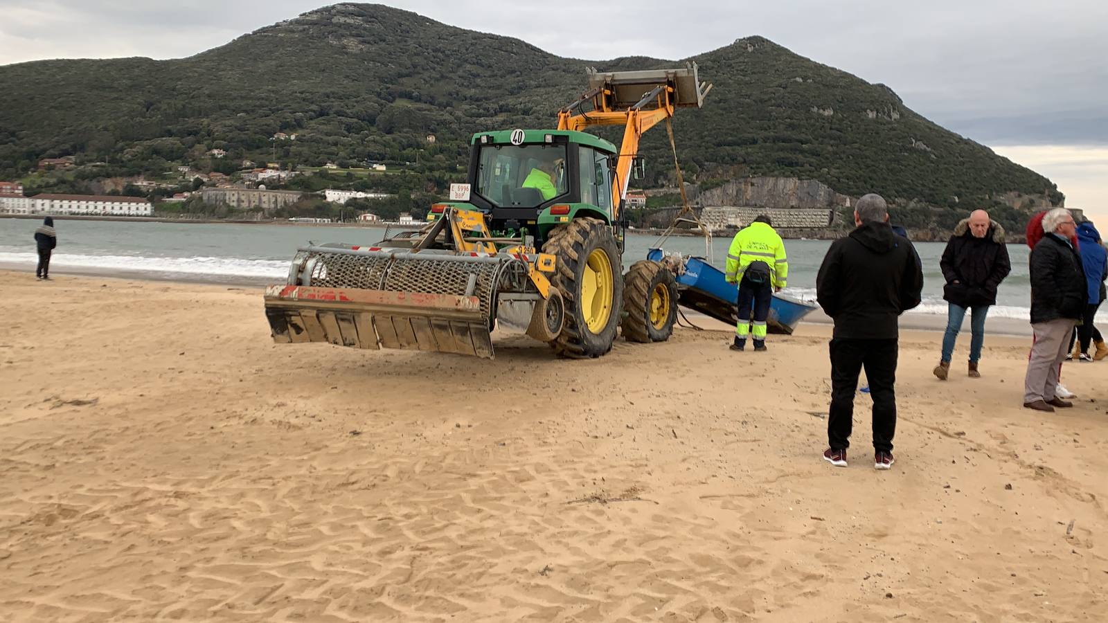 Una excavadora retira la barca de la playa, para llevarla a la explanada del Náutico.