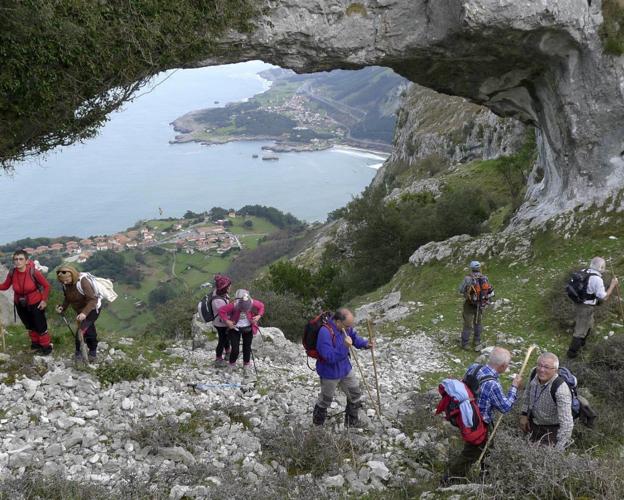 Un grupo de senderistas observan el Cantábrico y la zona de Sonabia e Islares desde uno de los ojos.