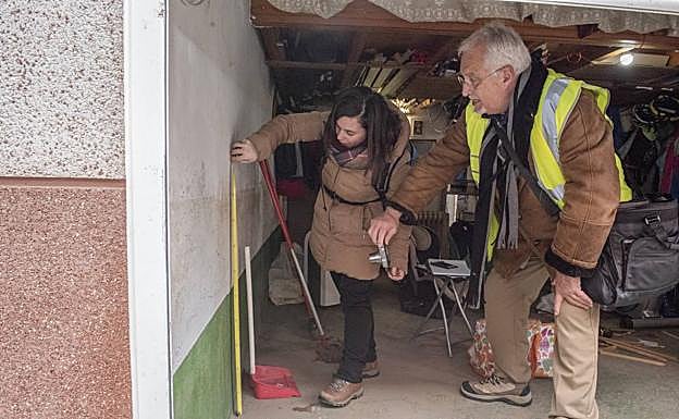 Dos técnicos miden la altura a la que durante la riada llegó el agua en uno de los garajes inspeccionados