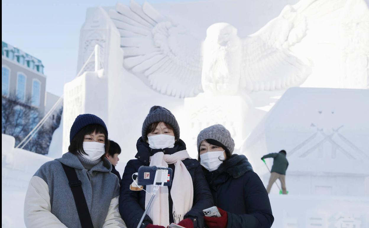 Tres turistas se fotografían con una de las grandes esculturas hechas con nieve que cada año realizan los soldados de las fuerzas locales de autodefensa para el festival.