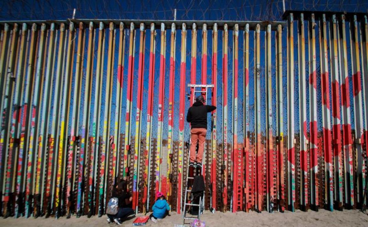 Personas pintan el muro fronterizo este sábado como parte de la actividad 'Muro de la Hermandad' en la cuidad de Tijuana, en Baja California (México). 