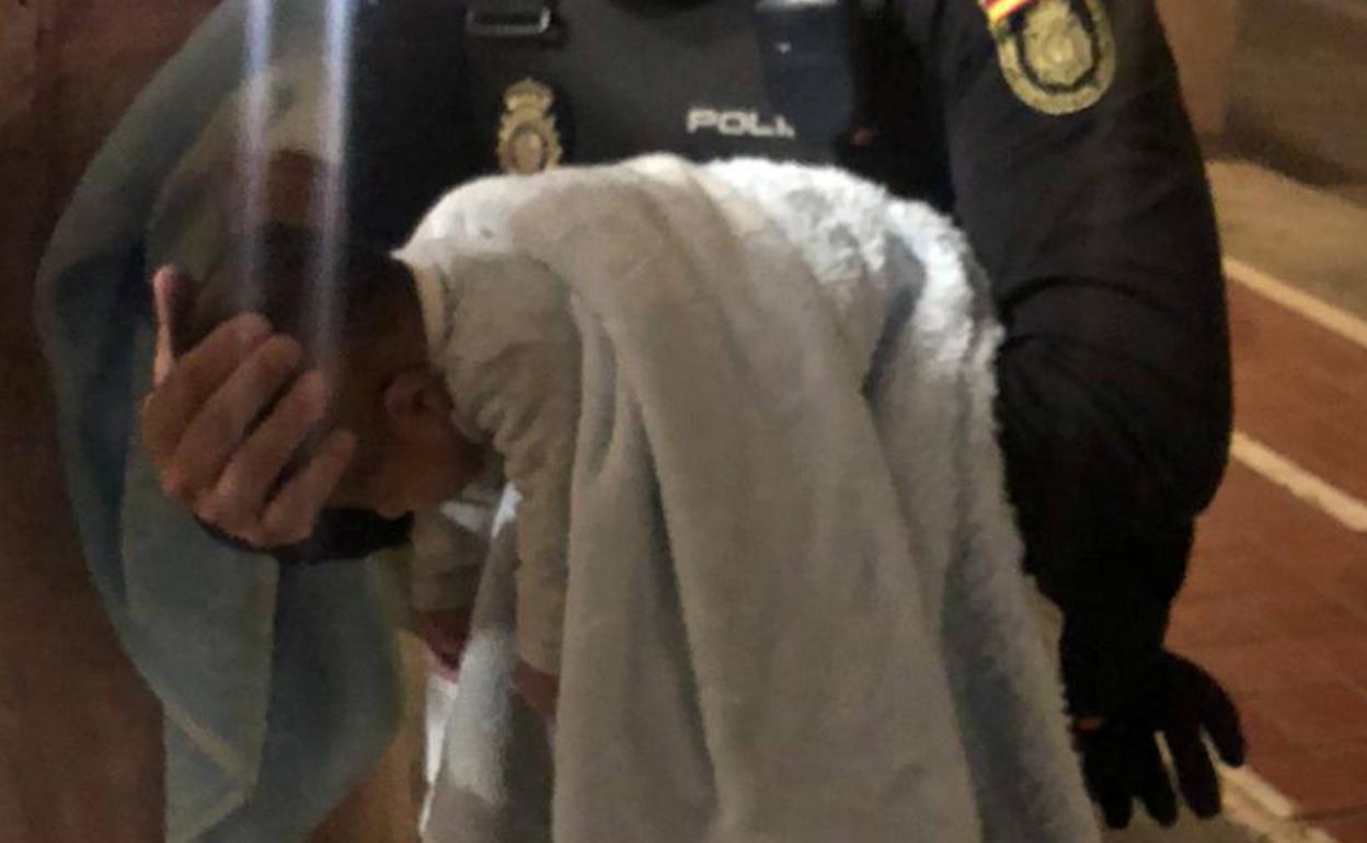 El bebe en brazos del policía nacional que le salvó la vida.