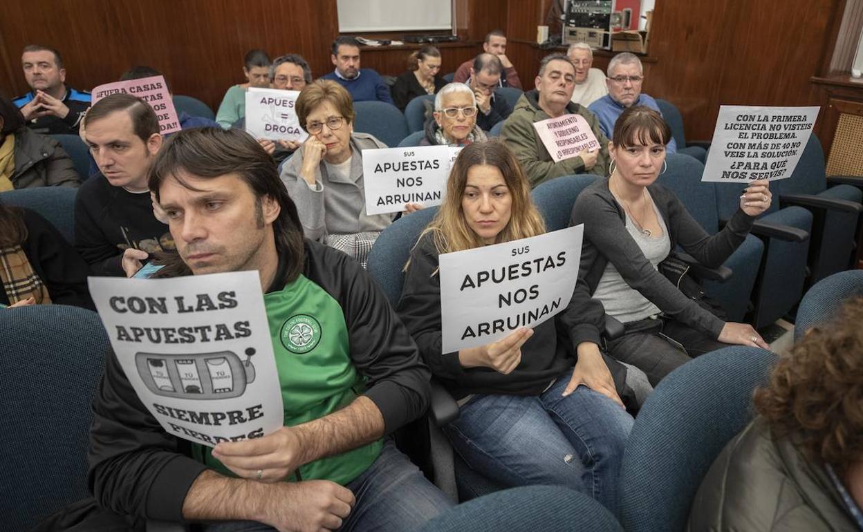 El debate ha sido seguido en el Salón de Plenos por varias personas que portaban carteles en contra de las salas de juego. 