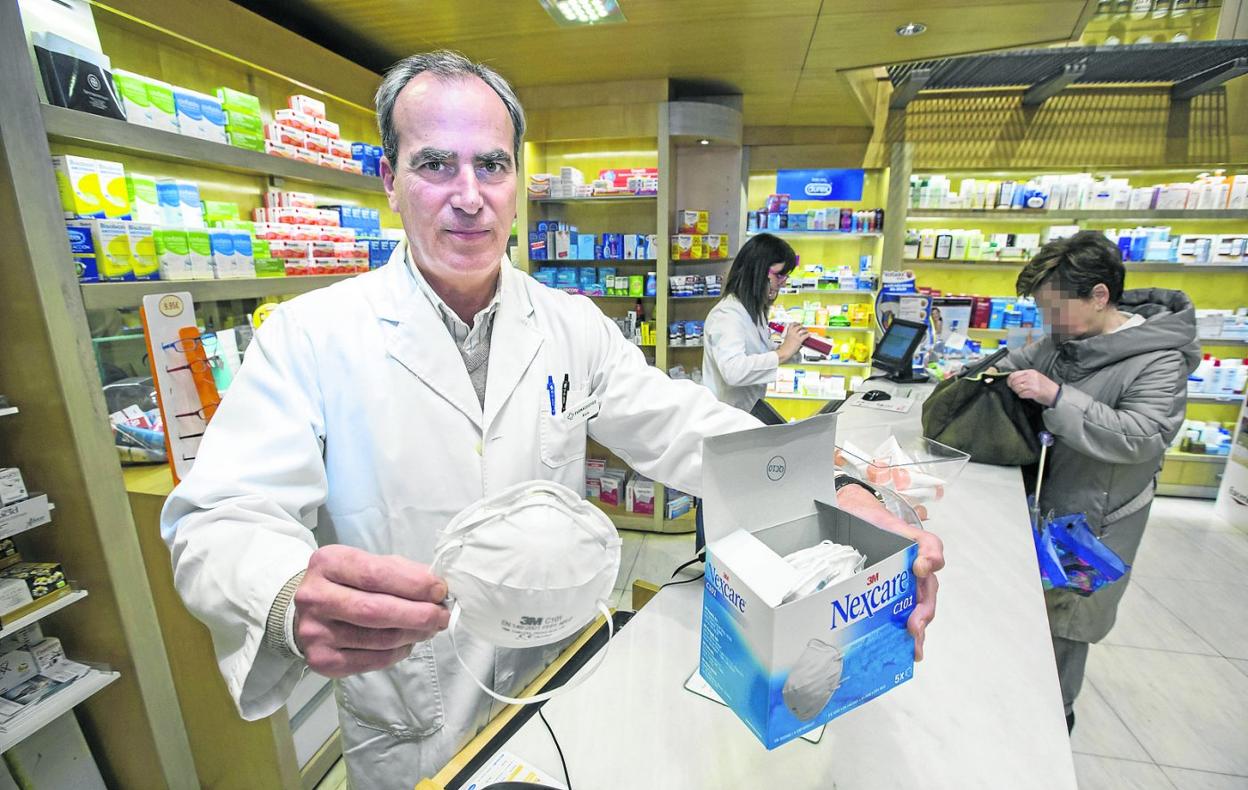 Un farmacéutico muestra unas mascarillas en su establecimiento situado en la calle San Fernando de Santander.