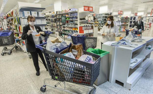 Trabajadores de El Corte Inglés organizando un pedido a domicilio, con medidas de protección de guantes y mascarilla.