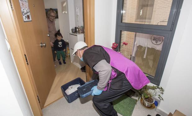 Un trabajador de Ampros realiza la entrega de uno de los menús y lo deposita a la entrada en un domicilio de Santander. celedonio