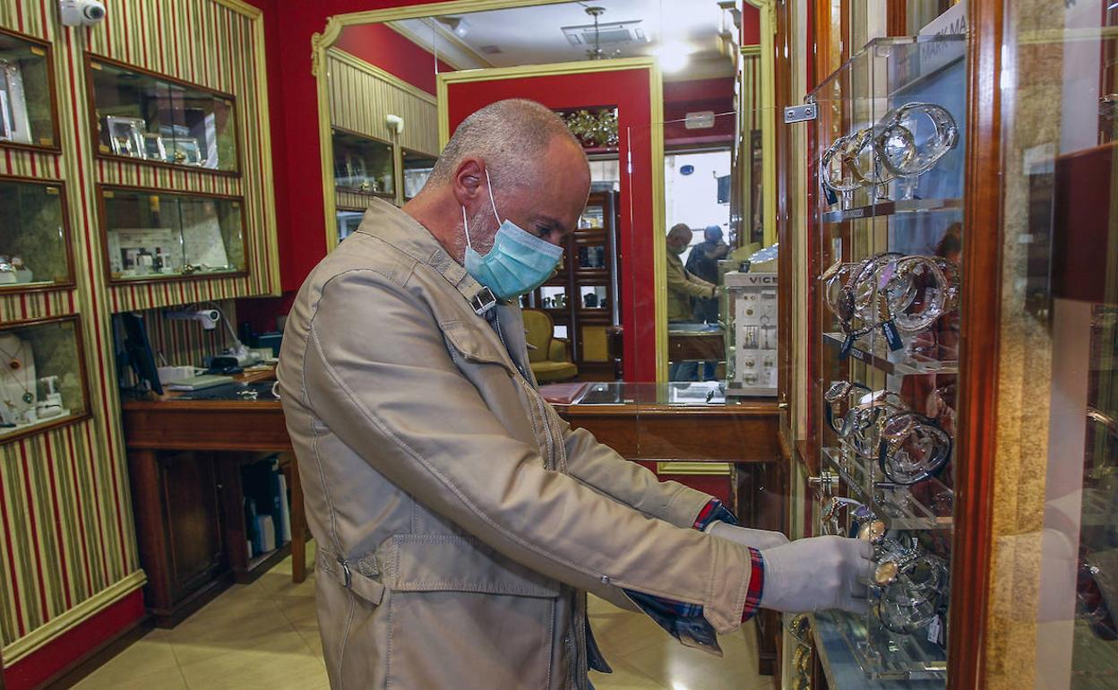 Ángel Fernández supervisa una vitrina con relojes en su joyería. 