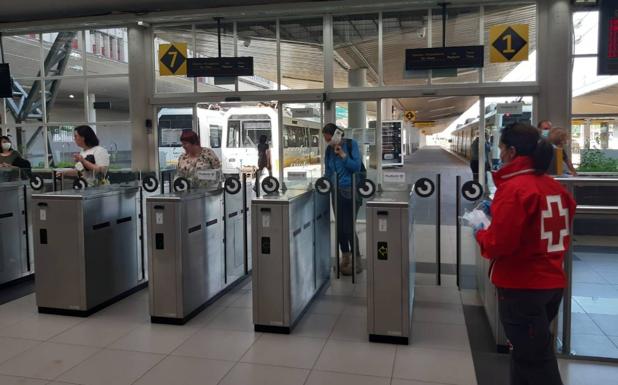 Una voluntaria de Cruz Roja reparte mascarillas en la estación de FEVE de Santander.