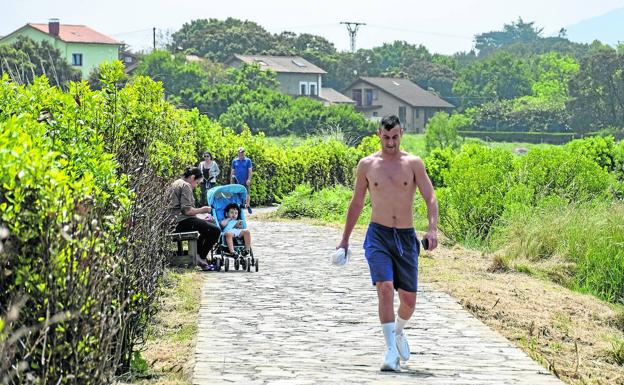 Vecinos de paseo por la senda costera que va desde Pontejos hasta Pedreña, recorriendo el litoral del municipio.