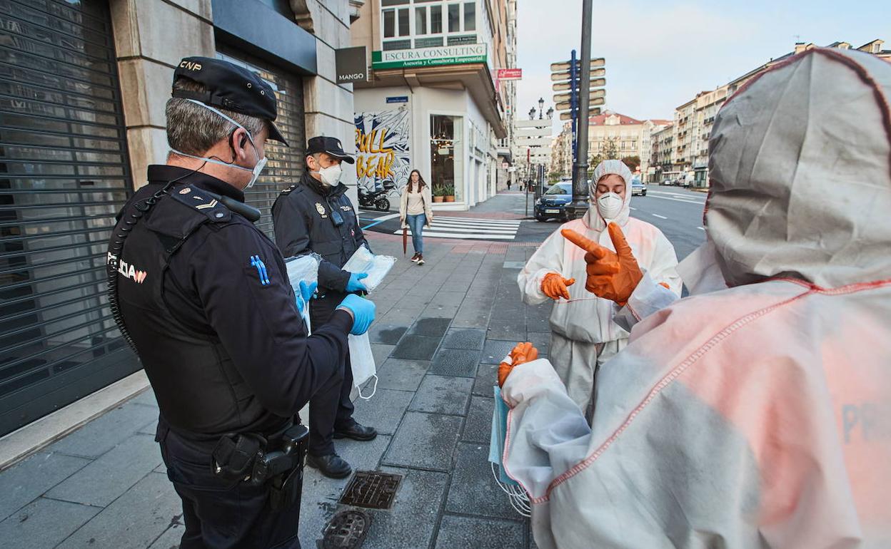 Dos policías nacionales reparten mascarillas.