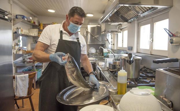 Pedro Guevara prepara un pescado en la cocina. 