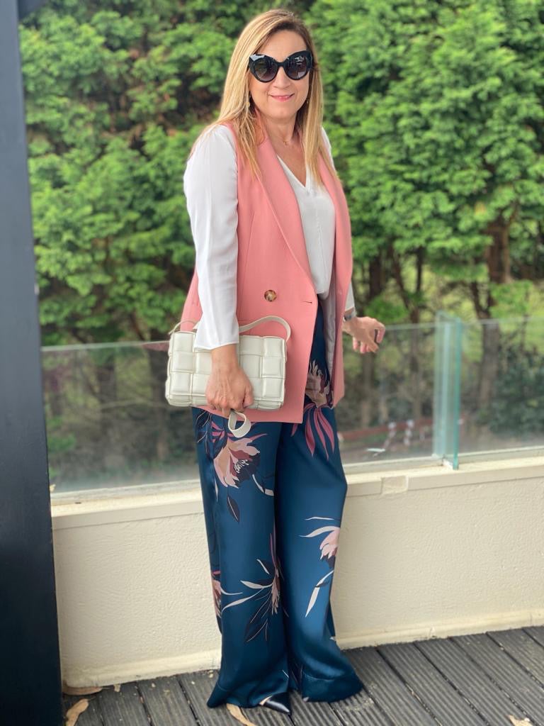 Para su look Rosa ha reutilizado prendas de otra temporada, cuya tendencia se repite: pantalón fluido de satén con estampado floral, camiseta básica blanca y todo combinado con chaleco en tono rosa marsala. Como complementos apuesta por el bolso en tono blanco hielo, inspirado en la firma Bottega Venetta, y zapatos tacón carrete combinados en tono negro y nude, muy en la línea de Chanel. 