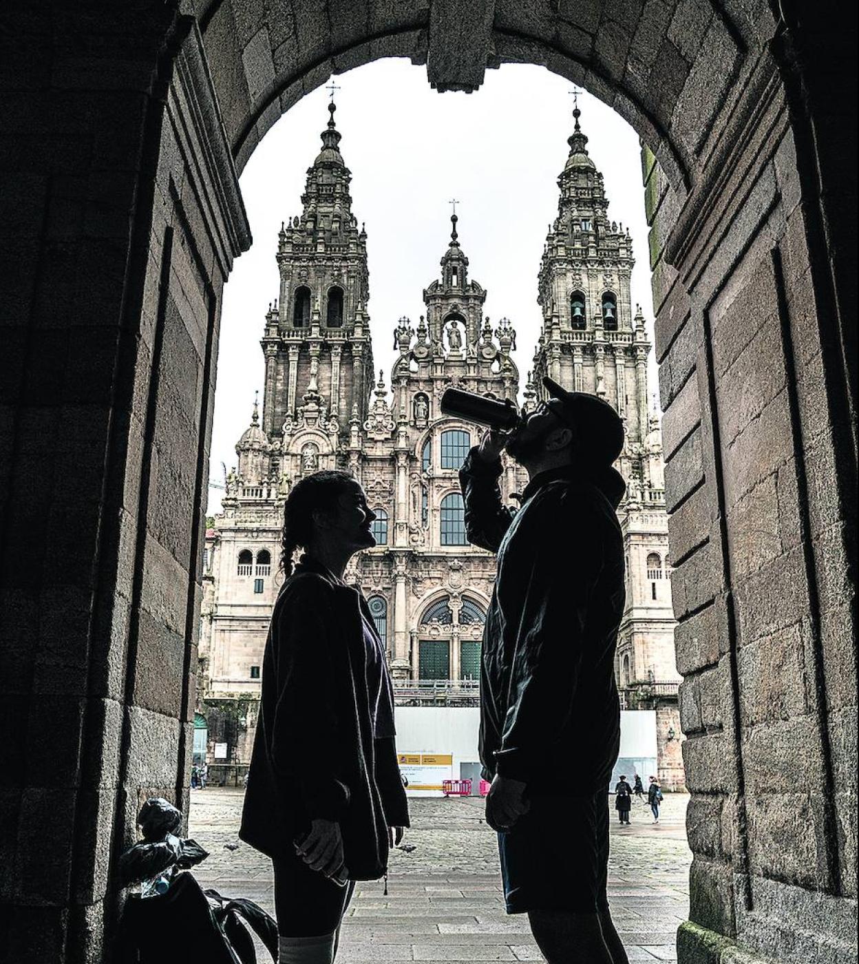 Una pareja recobra fuerzas frete a la catedral tras haber concluido el Camino.