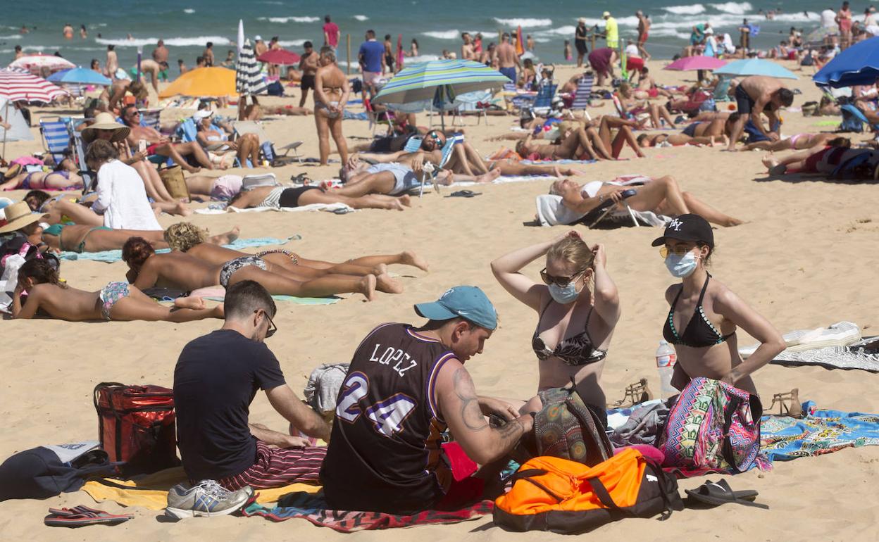 Imagen de la Primera playa de El Sardinero, con una afluencia numerosa y con dos jóvenes con la mascarilla