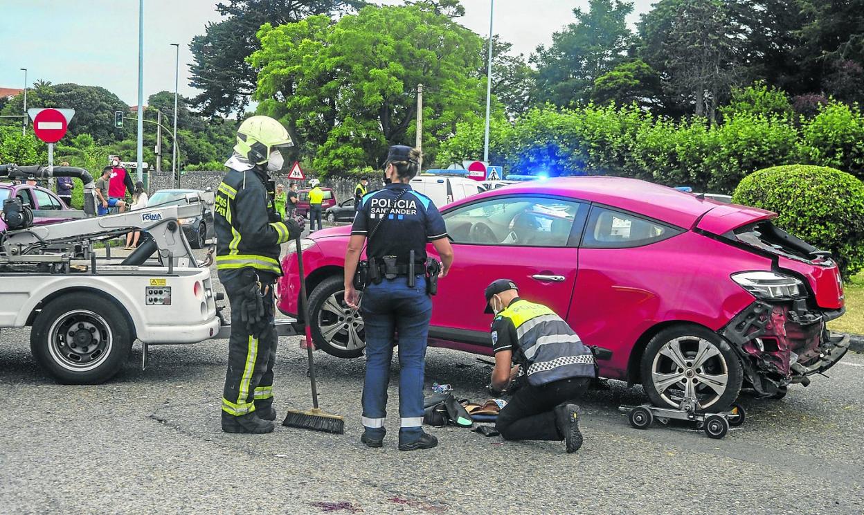 Bomberos y agentes de la Policía Local junto al vehículo siniestrado en el que viajaban las dos jóvenes. 