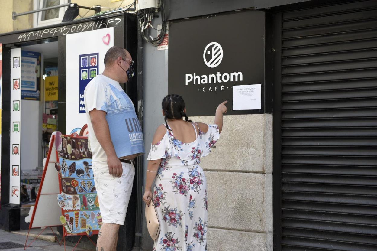 Dos clientes se detienen a leer la información del cartel explicativo colgado por los propietarios del Phantom, en Santander. 