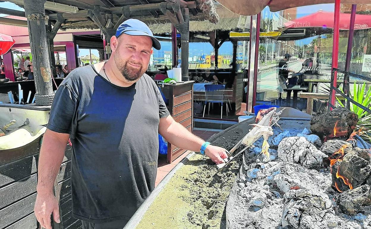 Antonio Cerdán vigila un espeto de sardinas y tres de pulpo en las brasas de su barca en el chiringuito María de Málaga.