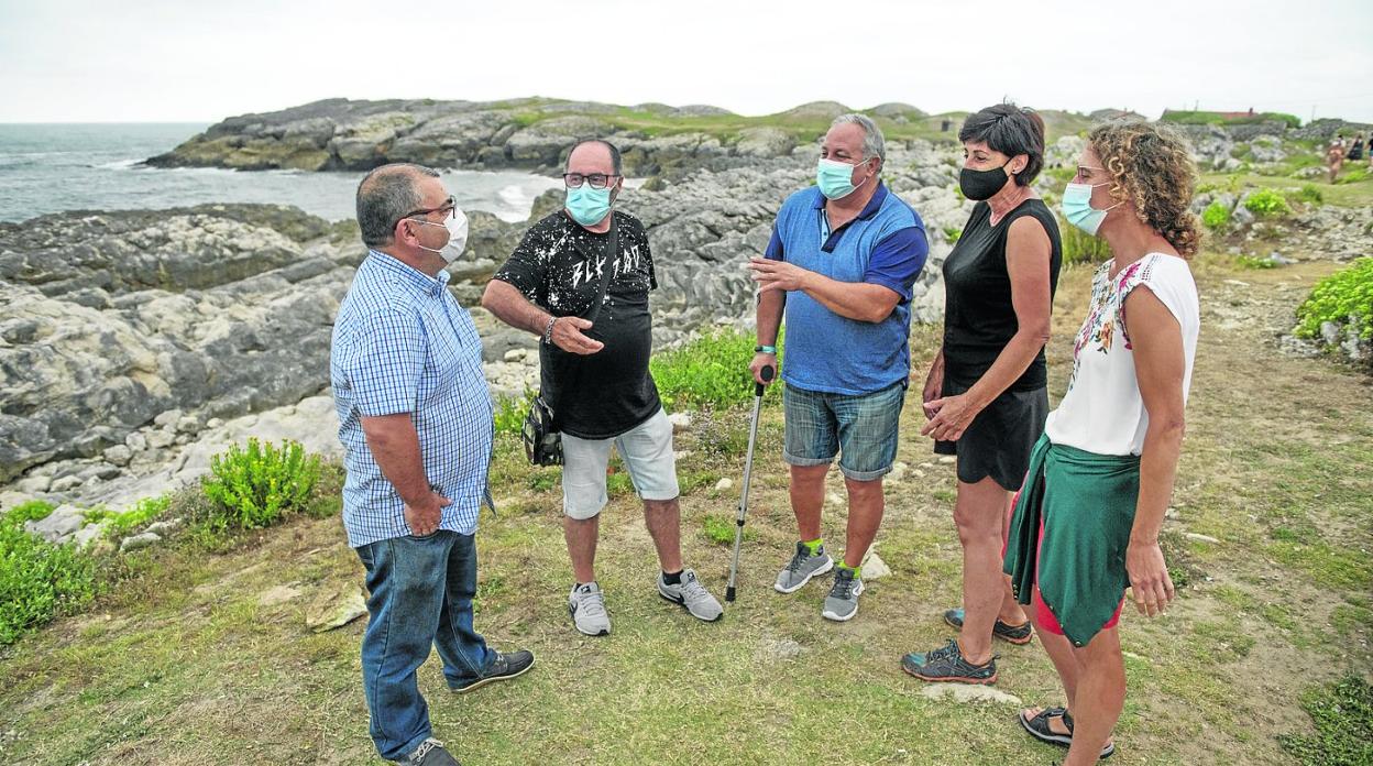 Vecinos de Monte y Cueto conversan en el aparcamiento del Bocal, con la playa escondida al fondo. 