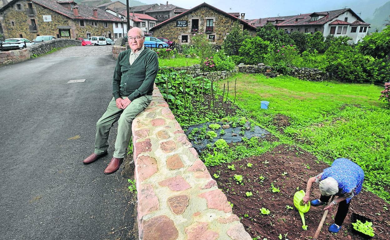 Fernando González posa en el pueblo de Carmona, mientras una vecina trabaja su huerta