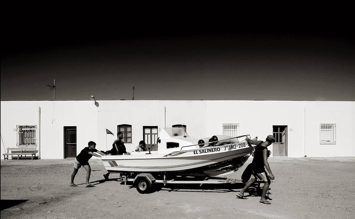 Una barca es empujada hacia el mar en el poblado de las Salinas del Cabo de Gata (Almería).