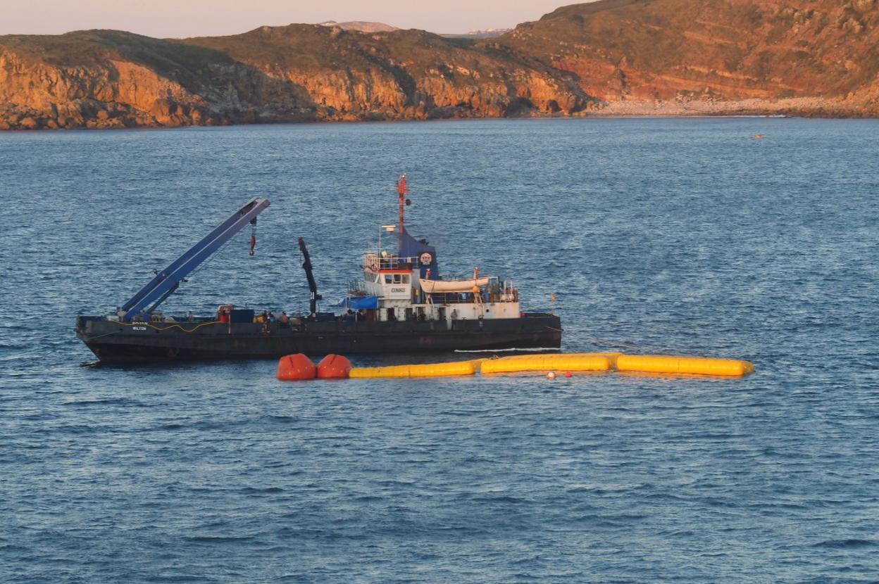 El barco encargado de los trabajos, este miércoles por la tarde, en aguas de Suances, junto a los flotadores que sustentan a la draga reflotada. 