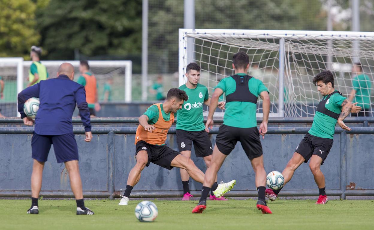 Óscar Gil se esfuerza en el centro del rondo en uno de los ejercicios sobre La Albericia. Rozada sigue de cerca la actividad de sus jugadores