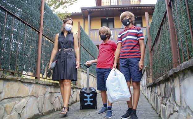 En familia. Le acompaña toda la familia a su primer día de colegio. Esperan a que su padre saque el coche.