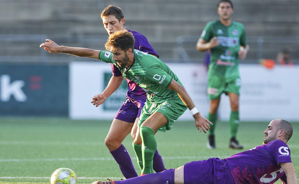 Iván Argos trata de controlar el balón ante dos jugadores del Santurtzi.