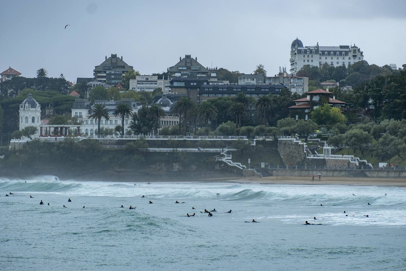 Llueve incesantemente en Cantabria y también hay grandes olas, que aprovechan los surfistas para pintar una de las estampas más habituales de Santander cuando el mar está embravecido.