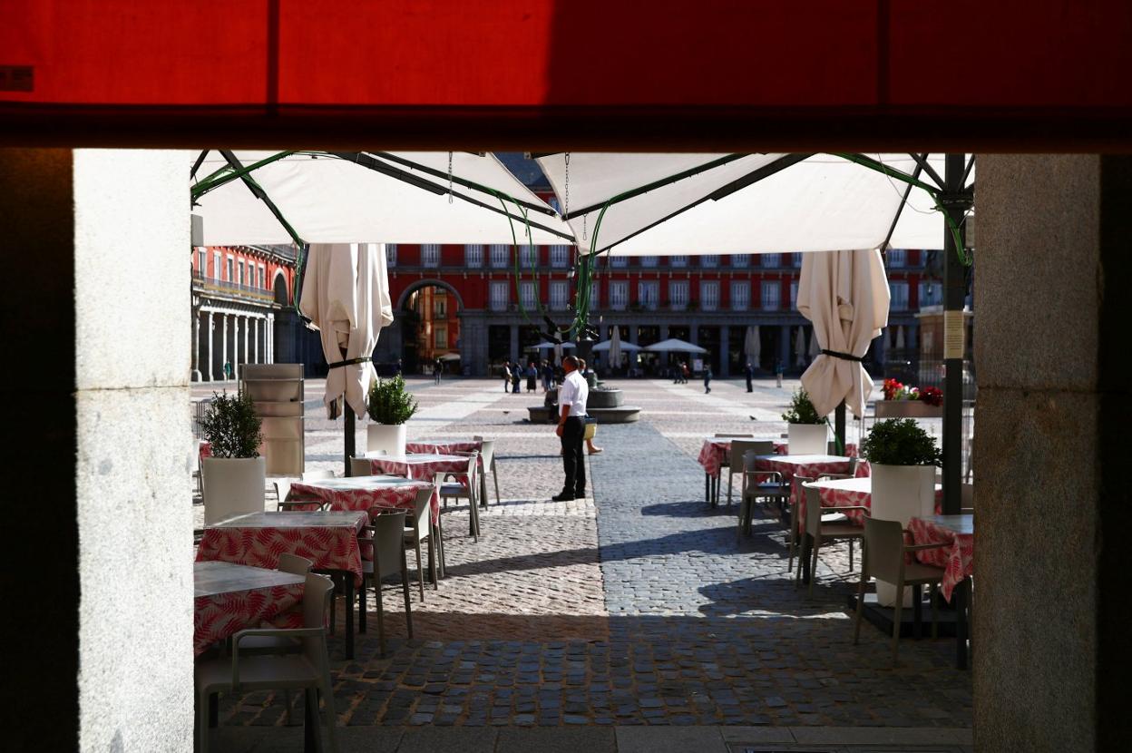 Un camarero espera la llegada de clientes en la Plaza Mayor de Madrid casi desierta. 