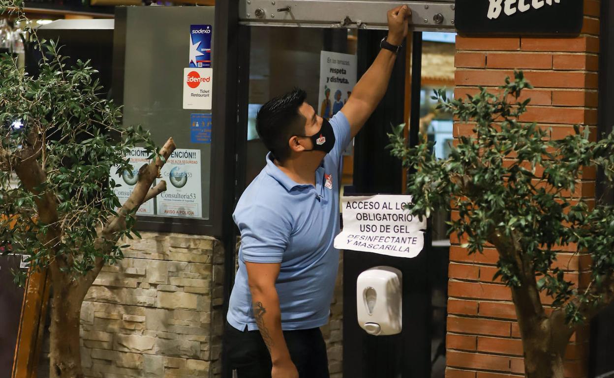 Un camarero baja la pesiana de un bar en Madrid.