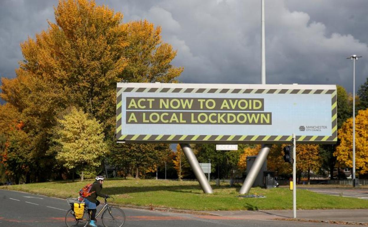 Una persona pasa por delante de un cartel de advertencia de covid en Manchester (Reino Unido) 