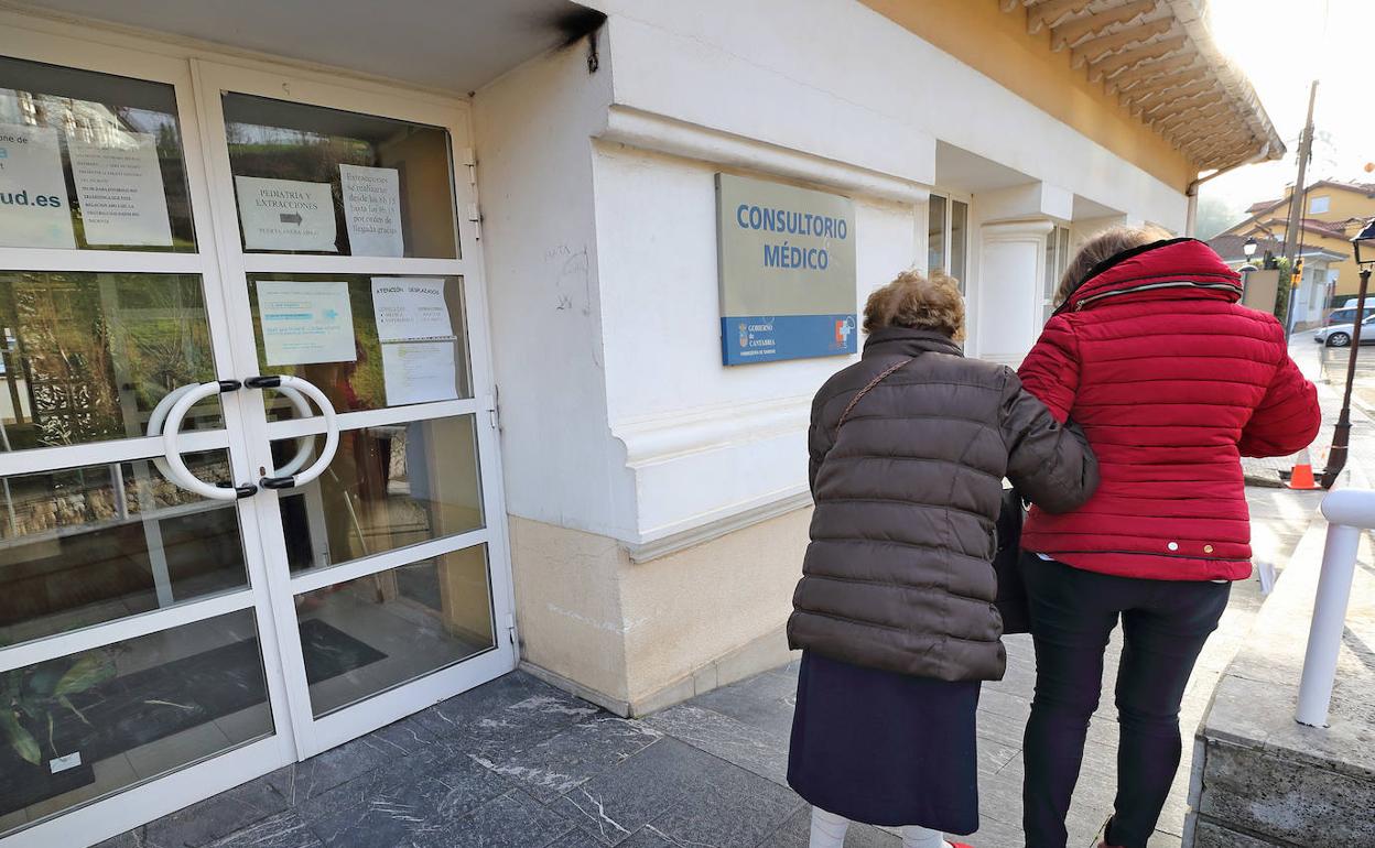 Una señora mayor sale acompañada del consultorio médico de Comillas. 