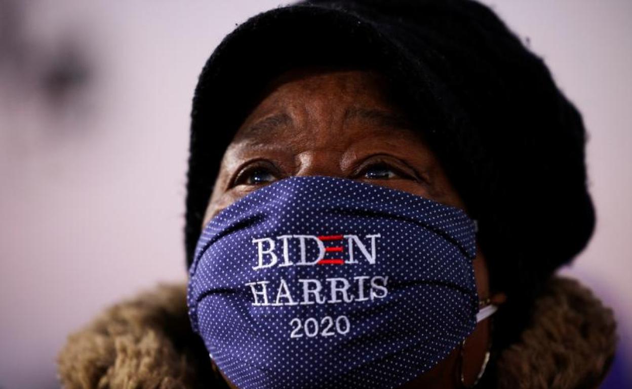 Un asistente con una máscara facial «Biden Harris 2020» observa al candidato presidencial demócrata 