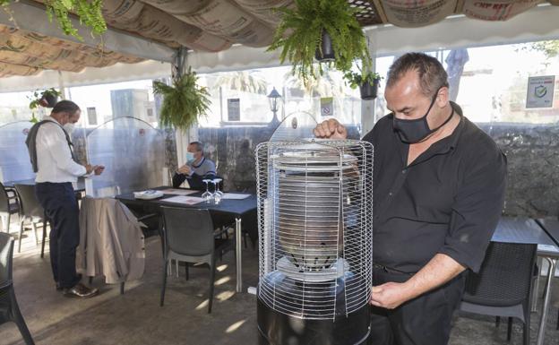 Uno de los trabajadores del restaurante La Parrilla de Hoznayo enciende una estufa de la terraza. 