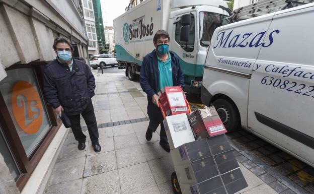 Un repartidor por las calles de Santander lleva un carro con cajas de botellas para distribuirlas a bares y restaurantes