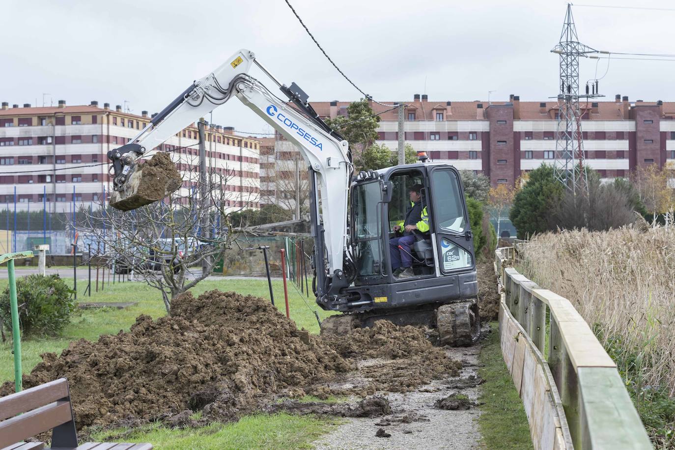 Operarios clavan tablones y extienden una capa de tierra a modo de dique para evitar que el agua vuelva a inundar el barrio de Santiago el Mayor (Nueva Montaña), mientras el vecindario sigue limpiando el barro, colocando sacos a las puertas de sus casas y los bomberos achican el agua acumulada en bajos y garajes.