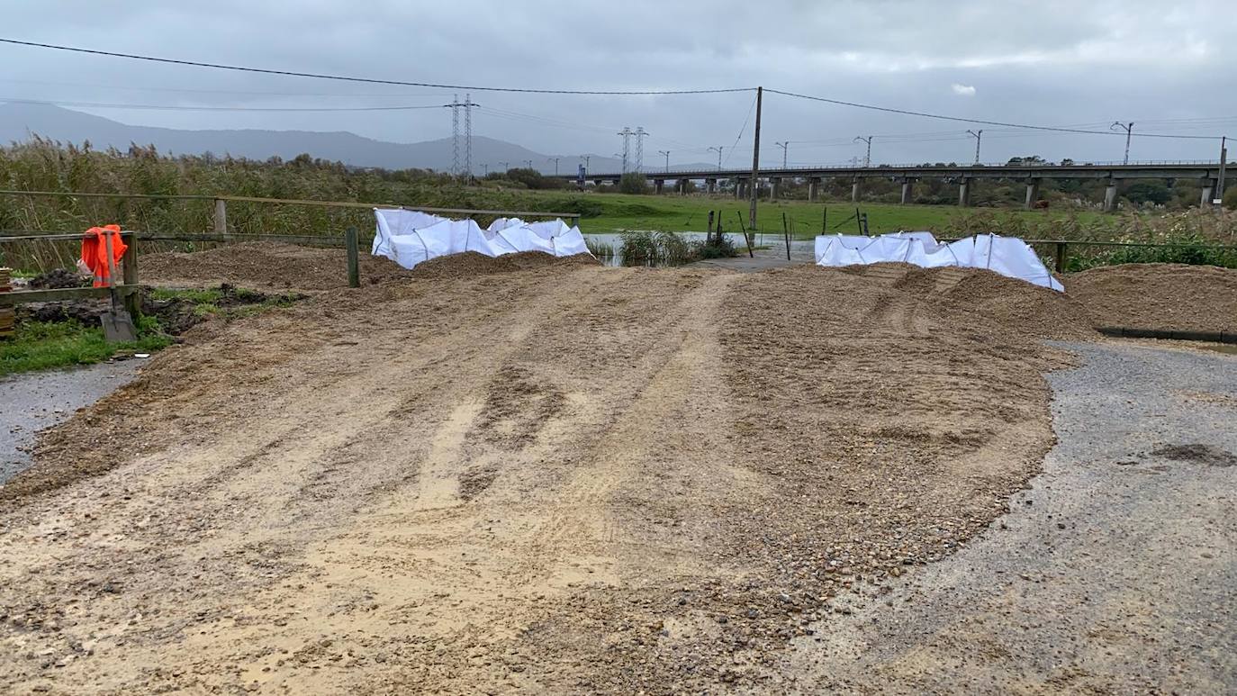 Operarios clavan tablones y extienden una capa de tierra a modo de dique para evitar que el agua vuelva a inundar el barrio de Santiago el Mayor (Nueva Montaña), mientras el vecindario sigue limpiando el barro, colocando sacos a las puertas de sus casas y los bomberos achican el agua acumulada en bajos y garajes.