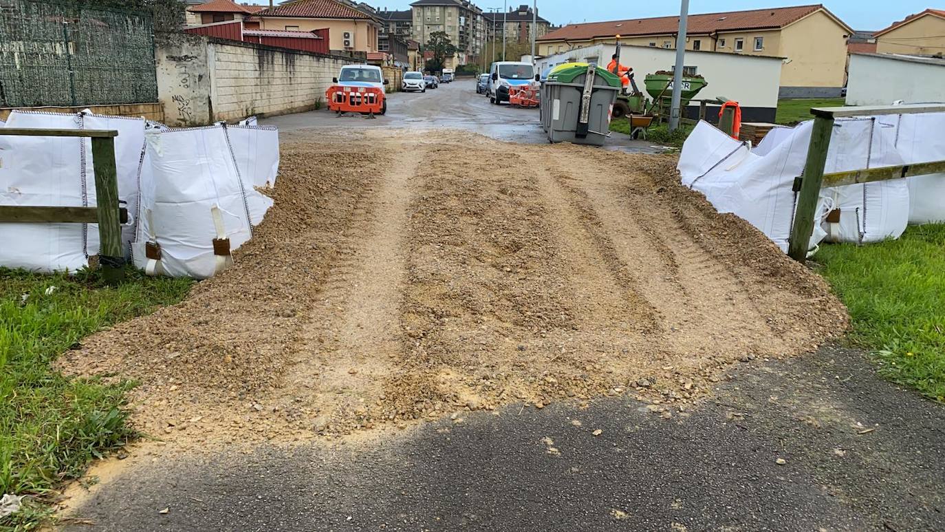 Operarios clavan tablones y extienden una capa de tierra a modo de dique para evitar que el agua vuelva a inundar el barrio de Santiago el Mayor (Nueva Montaña), mientras el vecindario sigue limpiando el barro, colocando sacos a las puertas de sus casas y los bomberos achican el agua acumulada en bajos y garajes.