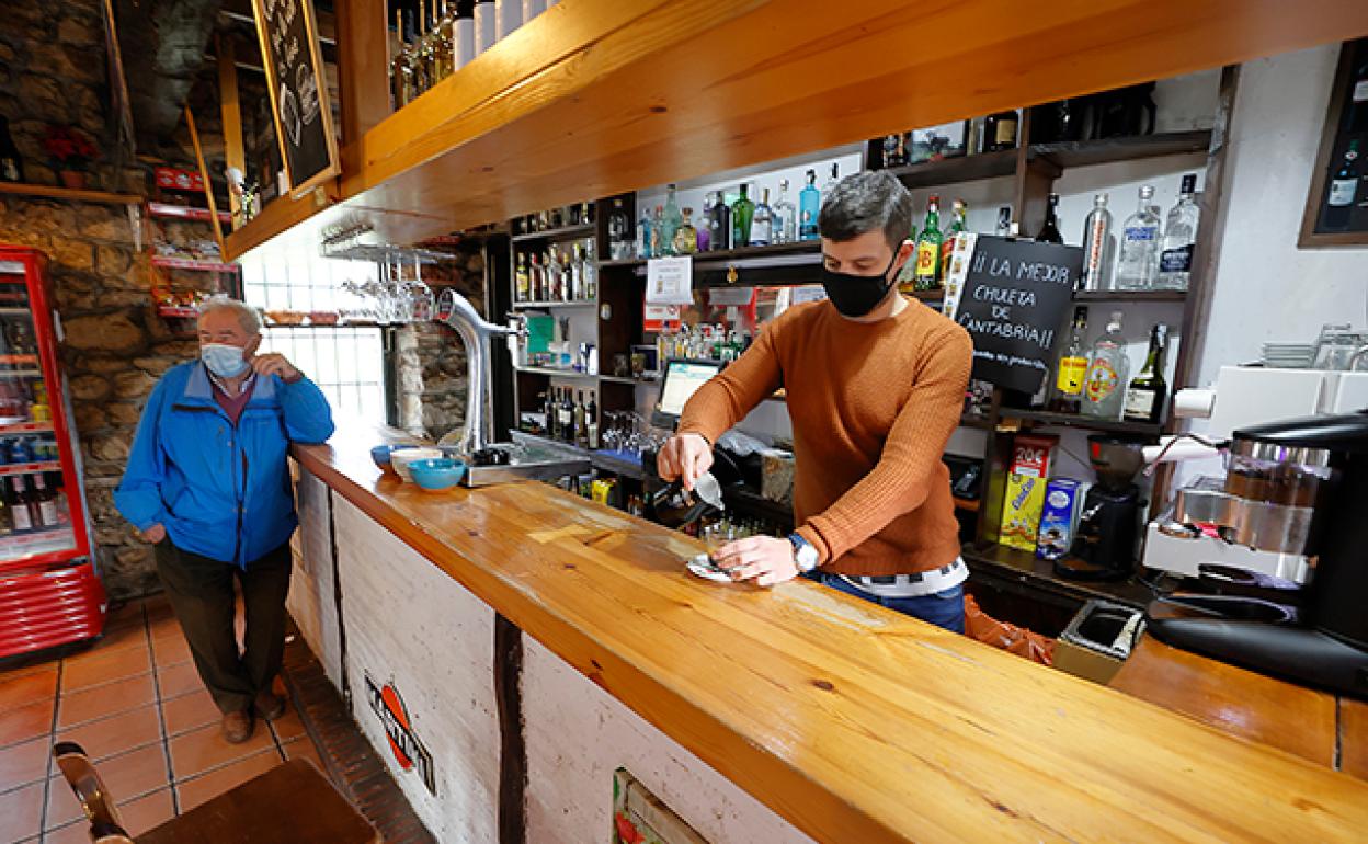 El propietario de la taberna Valle, en Cabuérniga, pone un café a un vecino. 