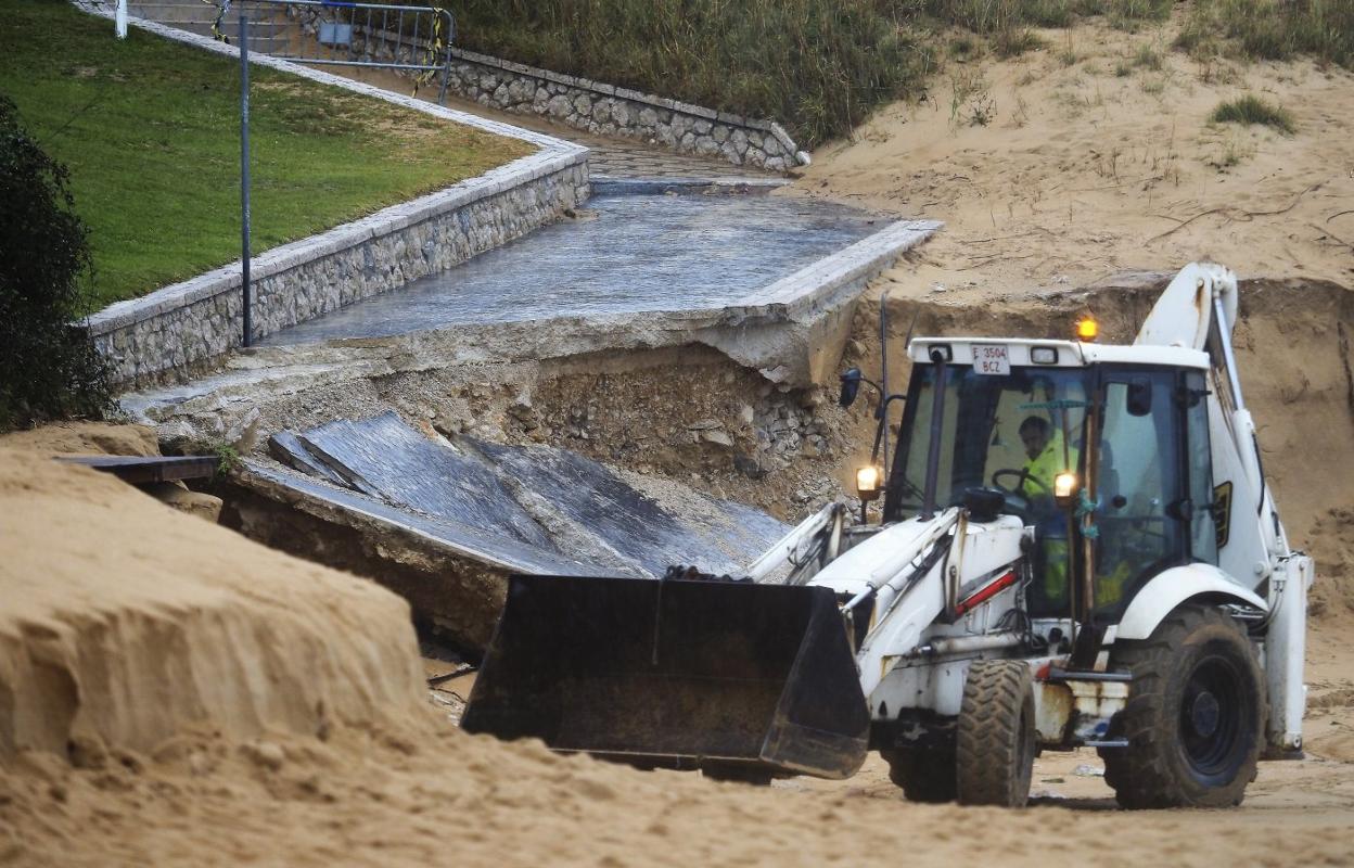 Un operario trabaja con una pala excavadora junto al tramo de la rampa de acceso a la playa de Los Peligros que se desprendió ayer. 