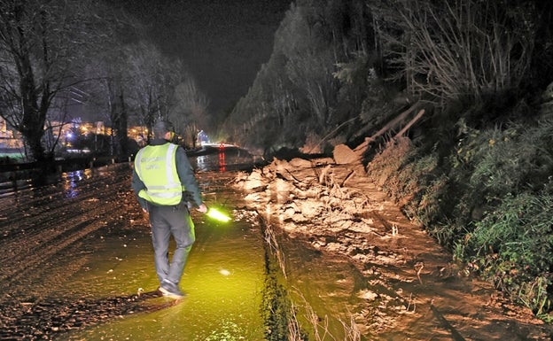 Un operario observa el argayo de barro que ocupa parte del carril derecho de la carretera. 