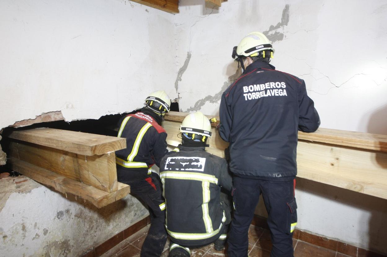 Los bomberos colocan grandes vigas debajo de la escalera. 